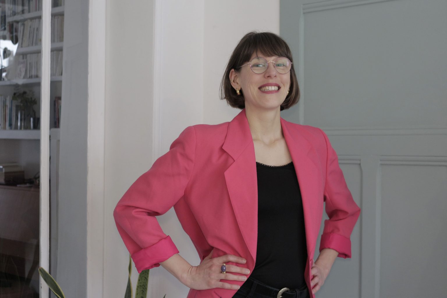 je suis souriante, les bras sur les hanches avec une veste rose